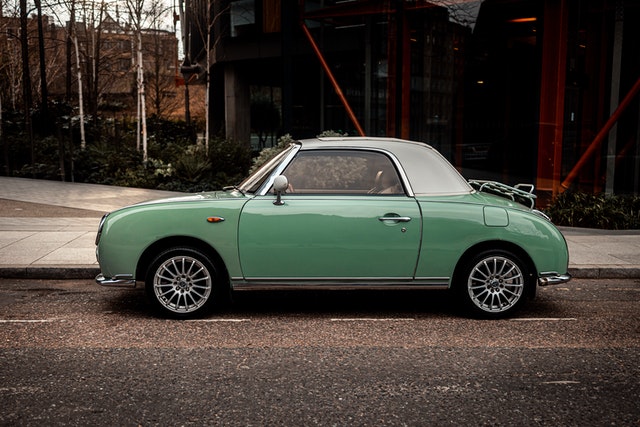 green-nissan-figaro-parked-on-gray-concrete-road