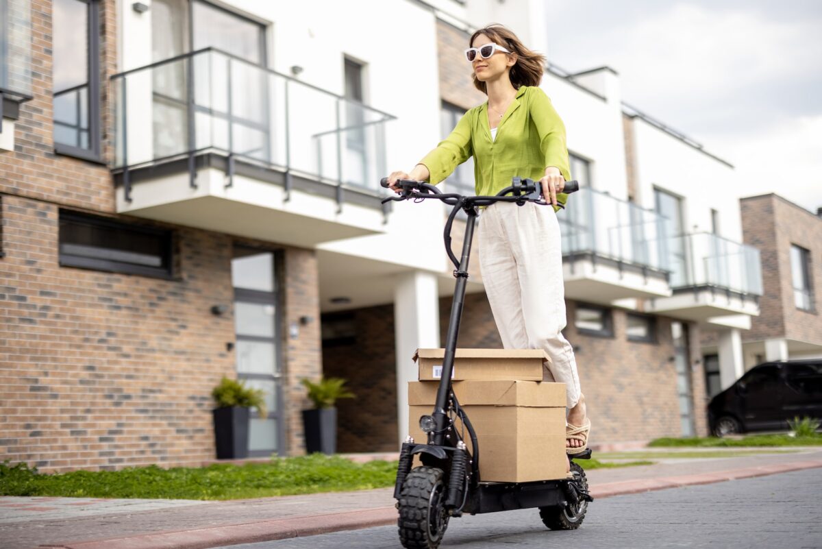 a girl on an electric scooter carries boxes