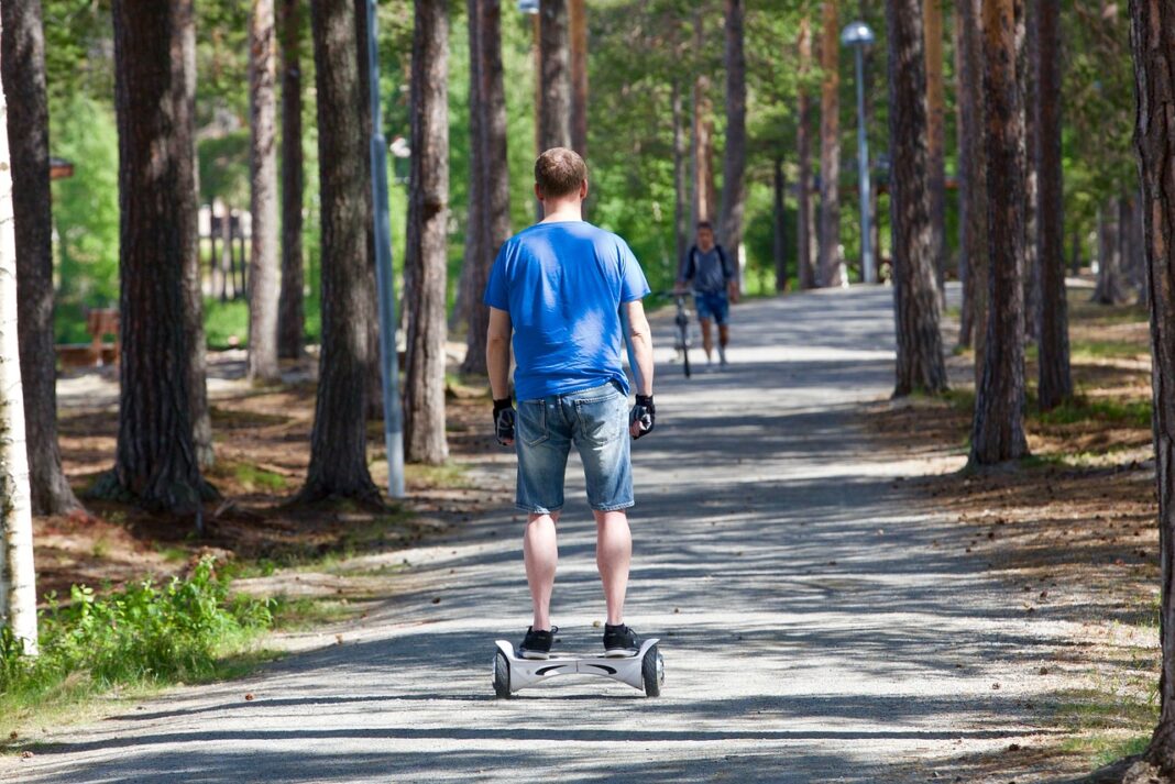 a man rides a hoverboard through the park